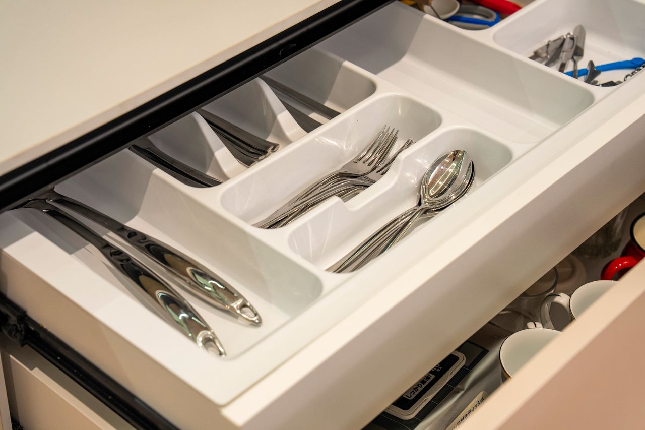 Neatly arranged silverware in a kitchen drawer with plastic organizer for efficient storage.