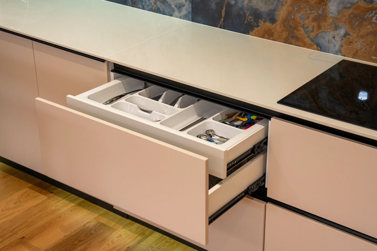 Mastering the First Impression: Your intriguing post title goes here Open kitchen drawer in modern kitchen with organized cutlery and utensils.